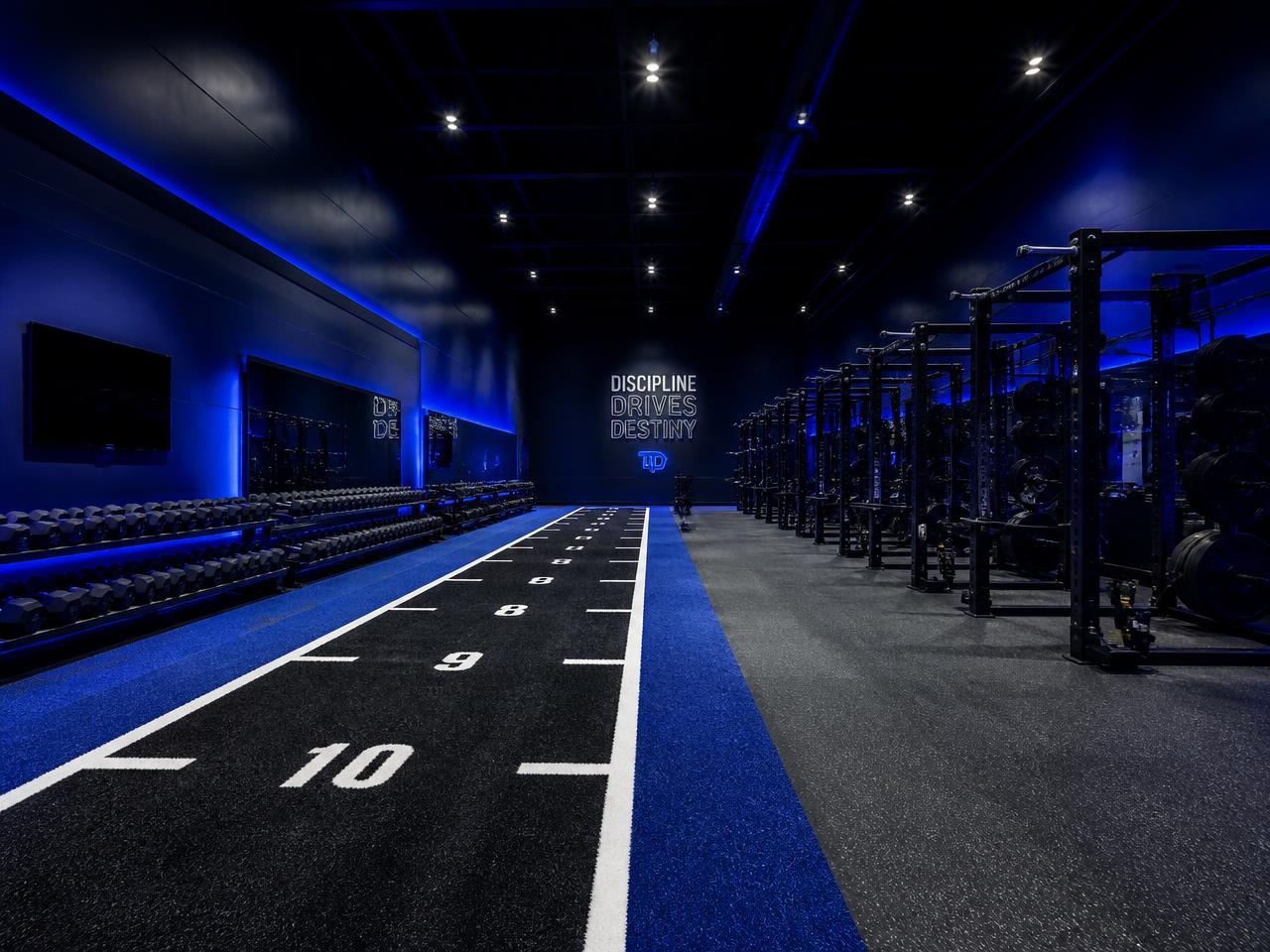 Private performance facility with turf sprint lane, racks, and dumbbells